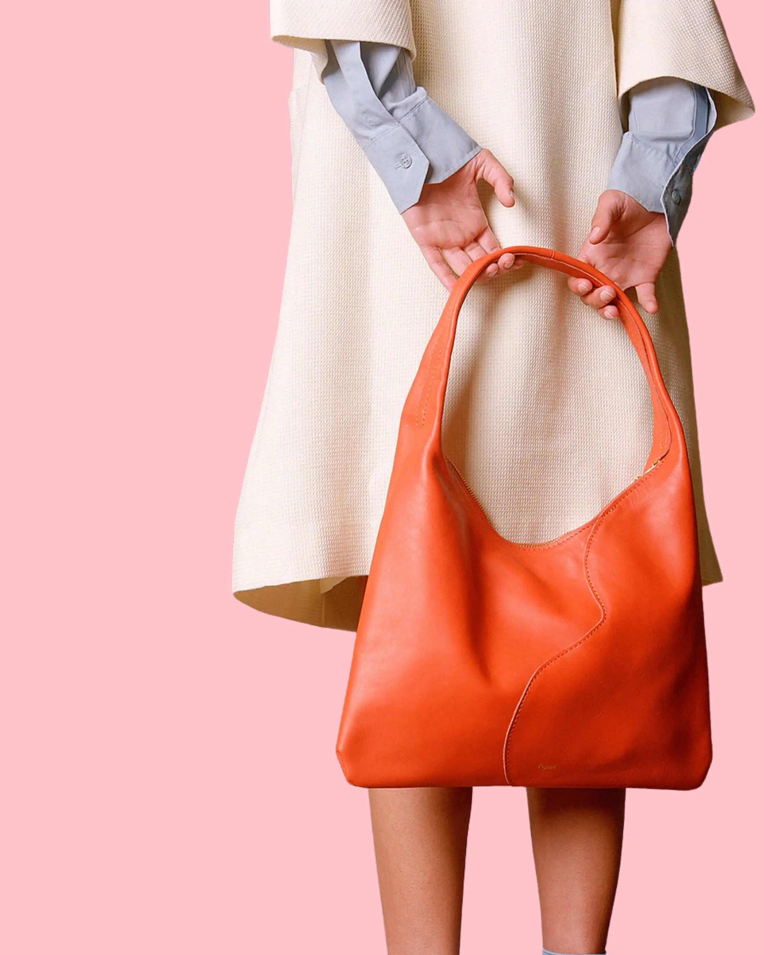 Woman holding a sculptural red bag against a pink backdrop