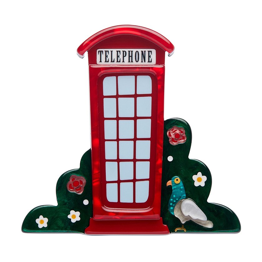 A brooch shaped like a vibrant red telephone booth, surrounded by green foliage with floral details, hand-assembled using resin, representing London’s iconic charm.