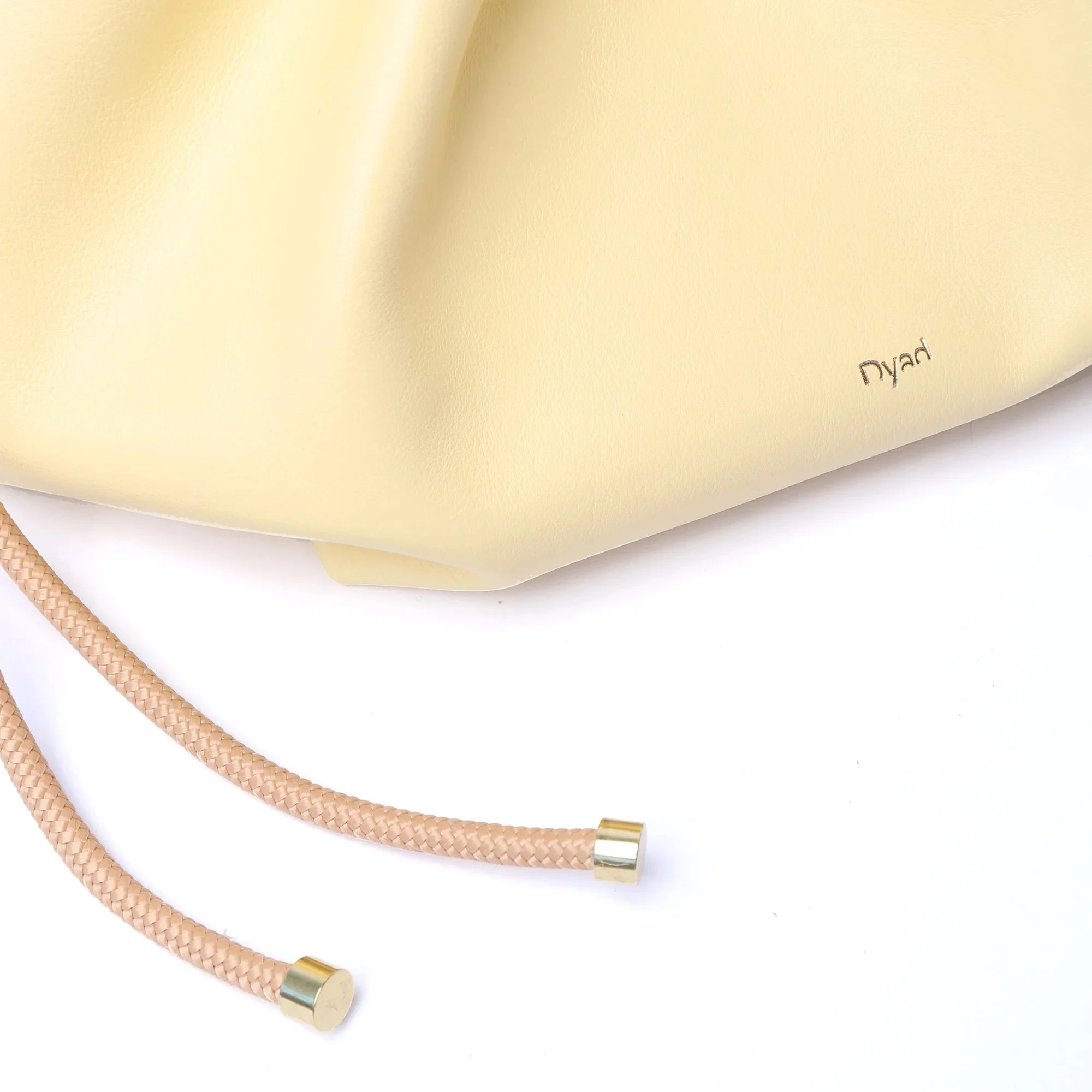 Butter yellow Flora Bag with tulip-style opening, handcrafted leather and adjustable rope strap by Project Dyad.