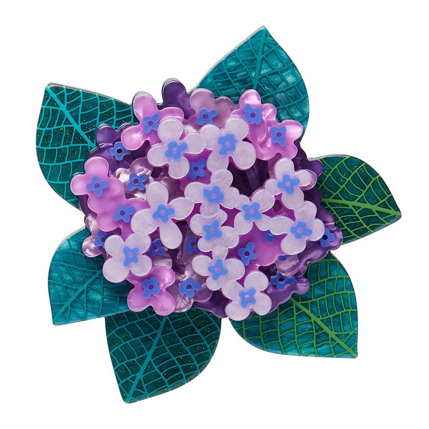 A brooch featuring lilac and purple hydrangea blooms surrounded by green leaves, made from layered resin, capturing the beauty of nature’s vibrant flora.