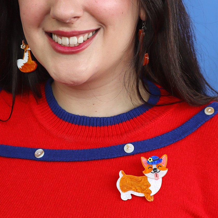 Susan the Corgi Brooch, featuring a smiling corgi with a bowler hat in white and orange resin. A playful addition to any brooch collection, perfect for corgi and British culture lovers.