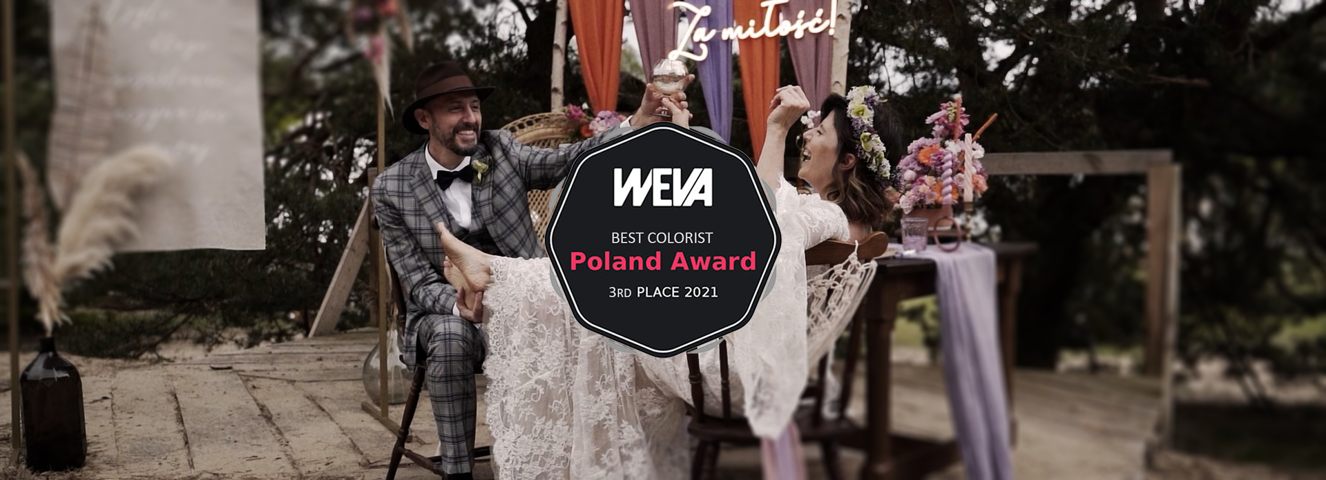 A couple celebrating at a wedding with a wooden outdoor setup, colorful decorations, and flowers, holding glasses of champagne.