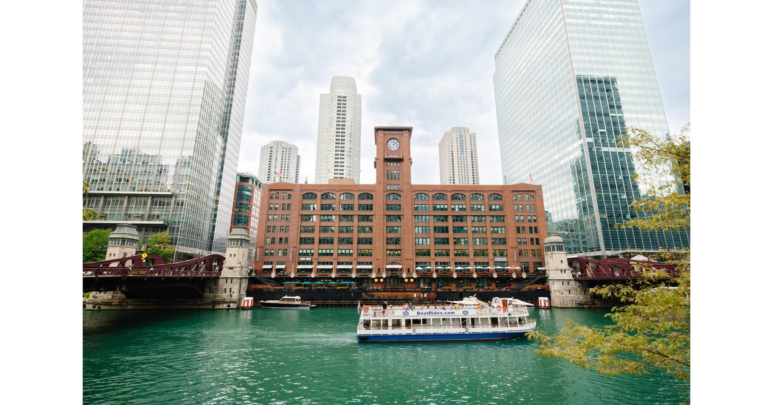 Photo of the Chicago River in the foreground with Merchandise Mart in the background, as ferry passes by on the river