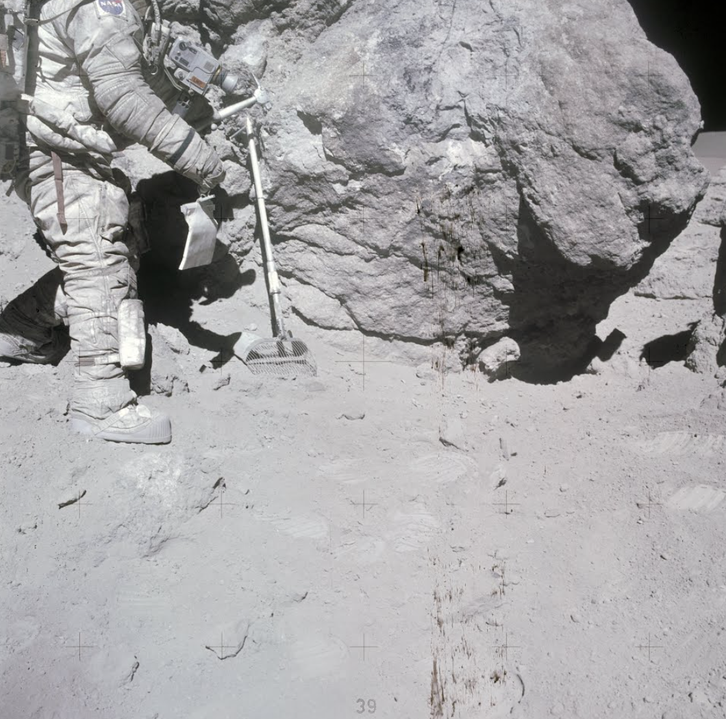 Astronaut Charles Duke stands at rock adjacent to "House Rock"
