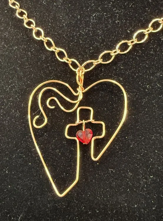 803-26;Necklace;’BCuHeartOfEaster’;UniqueHandCraftedFreeFormBCuRoundWire
HeartWithASwarovskiRedCrystalSuspendedBetweenTheArmsOfTheCrossAndFilagreeFlourishBesideTheCross;Chain24Inch;BCuTinyOvalAlternatingWithLargerIOvalInterlockingLinks;A2InchExtender
