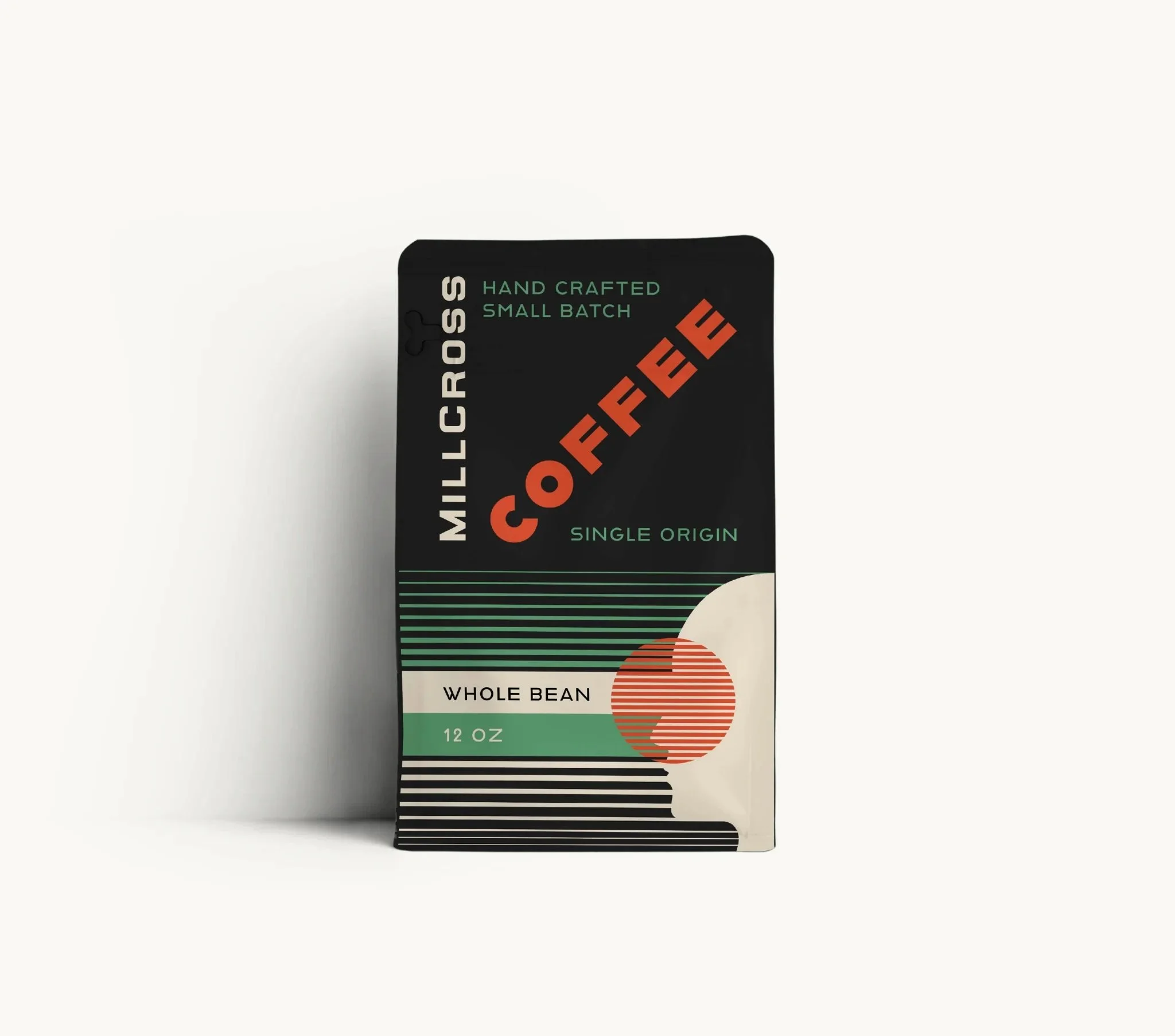 Black coffee package labeled "Millcrosse Coffee," featuring design elements including lines, a silhouette of a person's face, and orange circles, indicating whole bean, 12 oz.