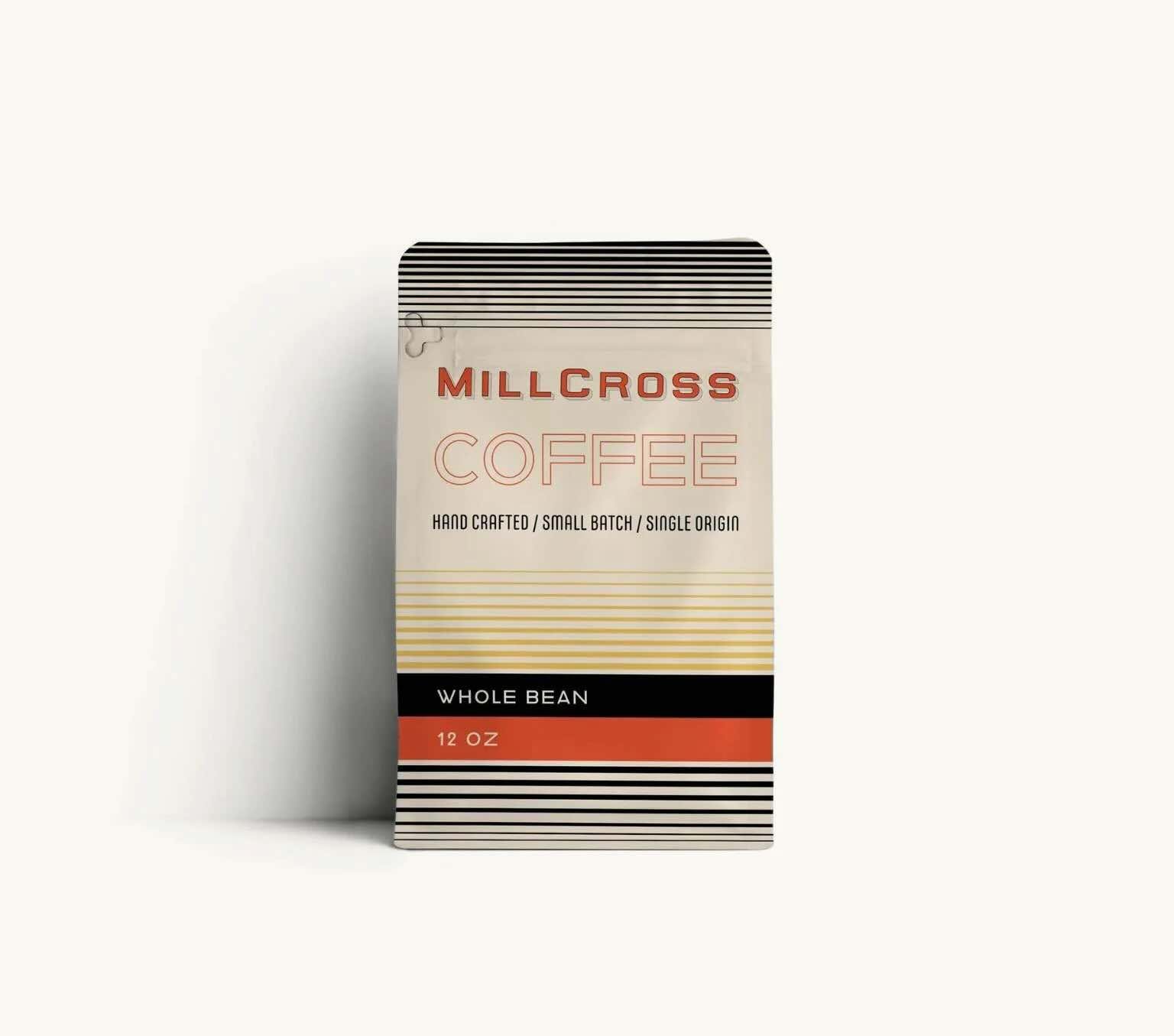 A bag of Millcross Coffee whole bean, 12 oz, in a beige and black striped package with red accents.