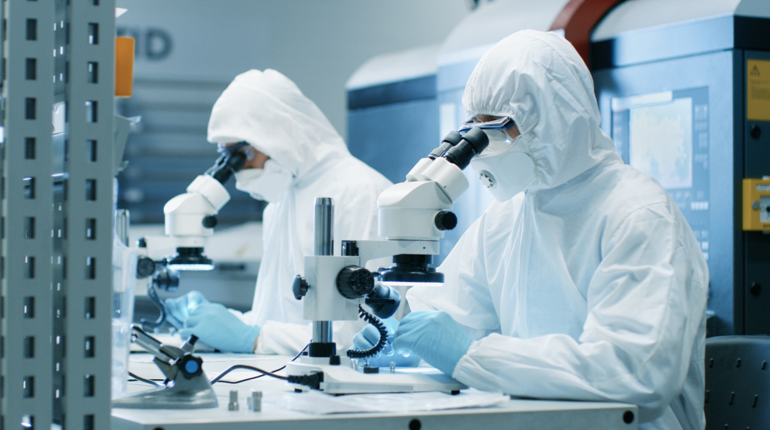 07 Sterile Suits Looking Down Microscopes.png