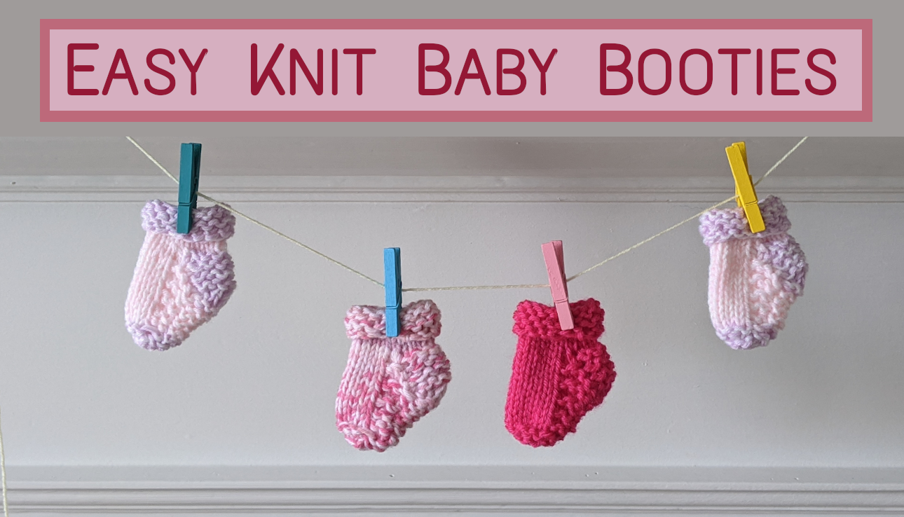 Hand-knit pink baby booties hanging from a clothesline