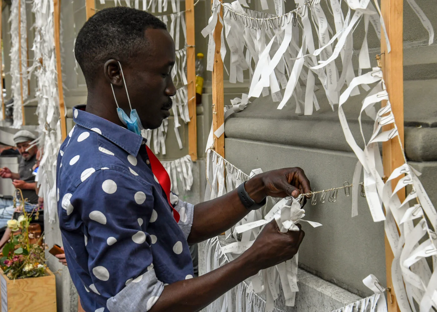 Eine Person steht an der Kirchenfassade und entfernt einzelne Stoffstreifen von den Schnüren.