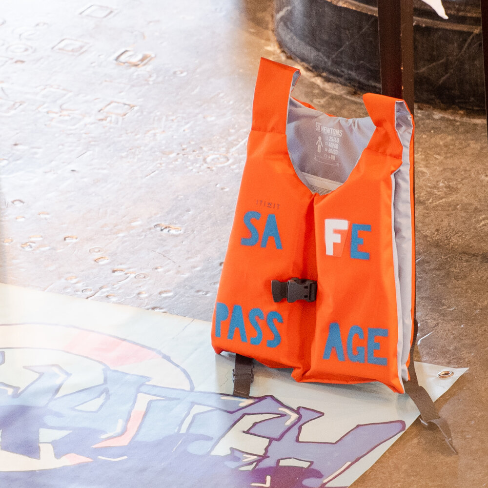 Eine Rettungsveste lehnt in der Heiliggeistkirche gegen den Rand des Podiums. Auf der Rettungsveste wurden mit grossen Buchstaben die Worte «Safe Passage» geschrieben
