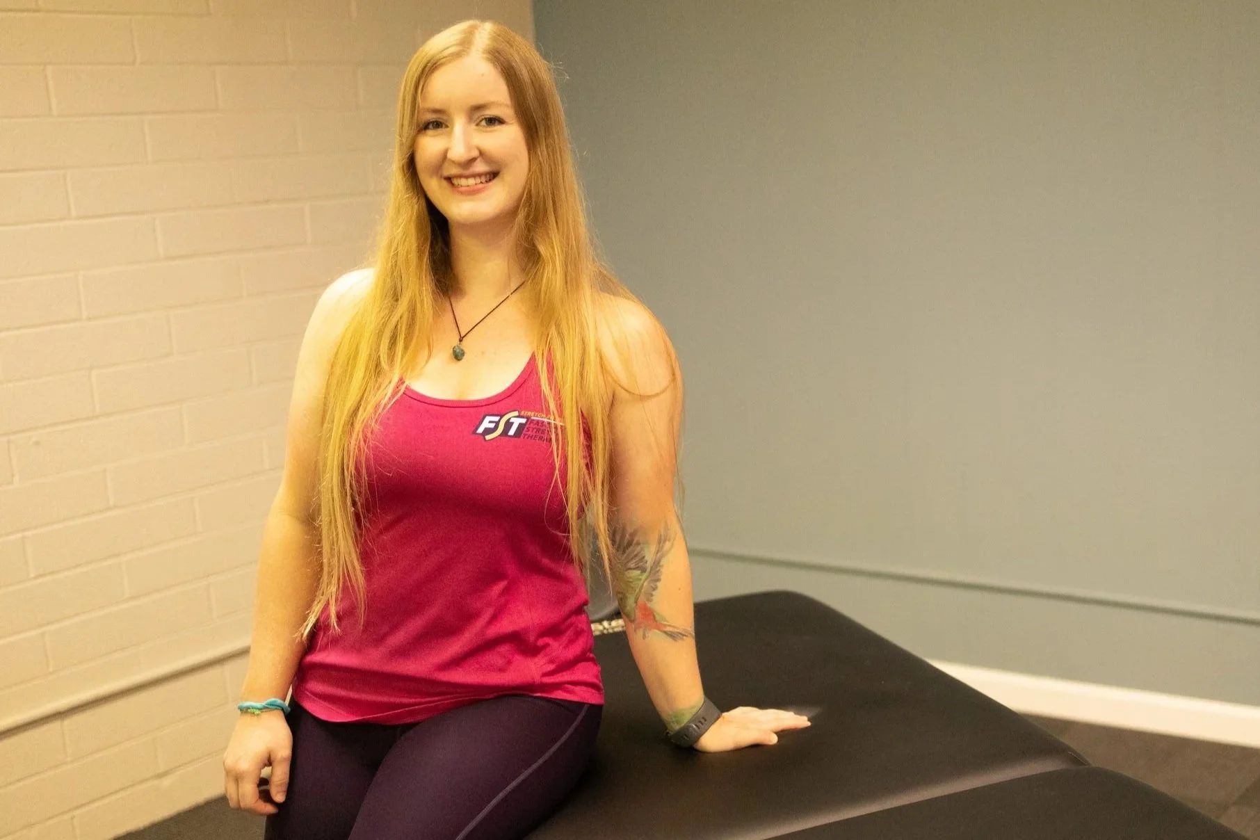 Tiffani Canevari sitting on a treatment table at Bodywork Remedies in Santa Rosa, CA before a fascia stretch therapy and bodywork session.