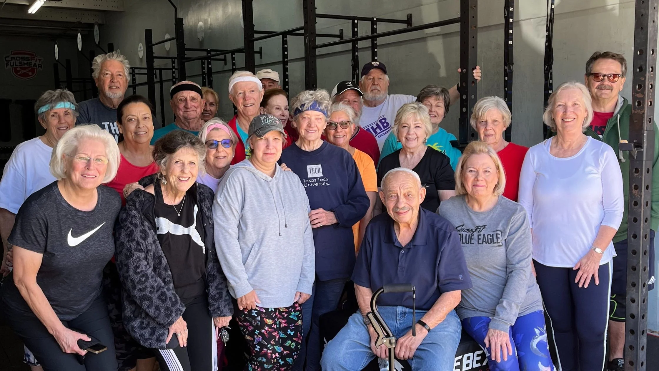 Group of older adults standing together inside a gym, smiling after a strength training session focused on community, movement, and healthy aging.