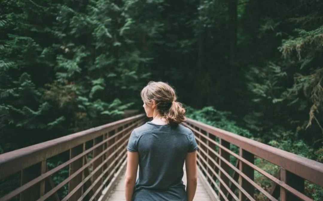 woman standing on wooden bridge with iron railings