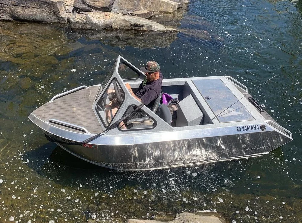 A completed Scout mini jet boat seen from above on the water beside rocks