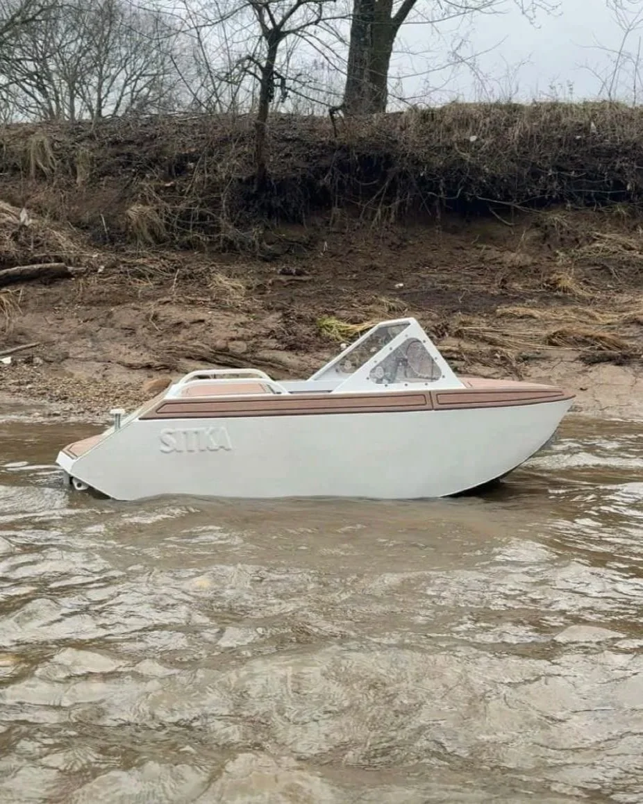 Completed white and tan Nano mini jet boat beside the river