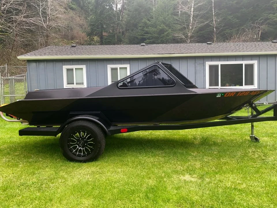 Side profile of a completed black Creekboat on its trailer