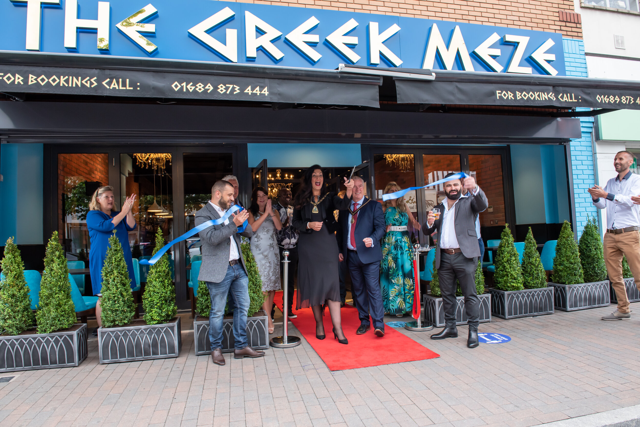 People cutting ribbon at The Greek Meze restaurant opening.