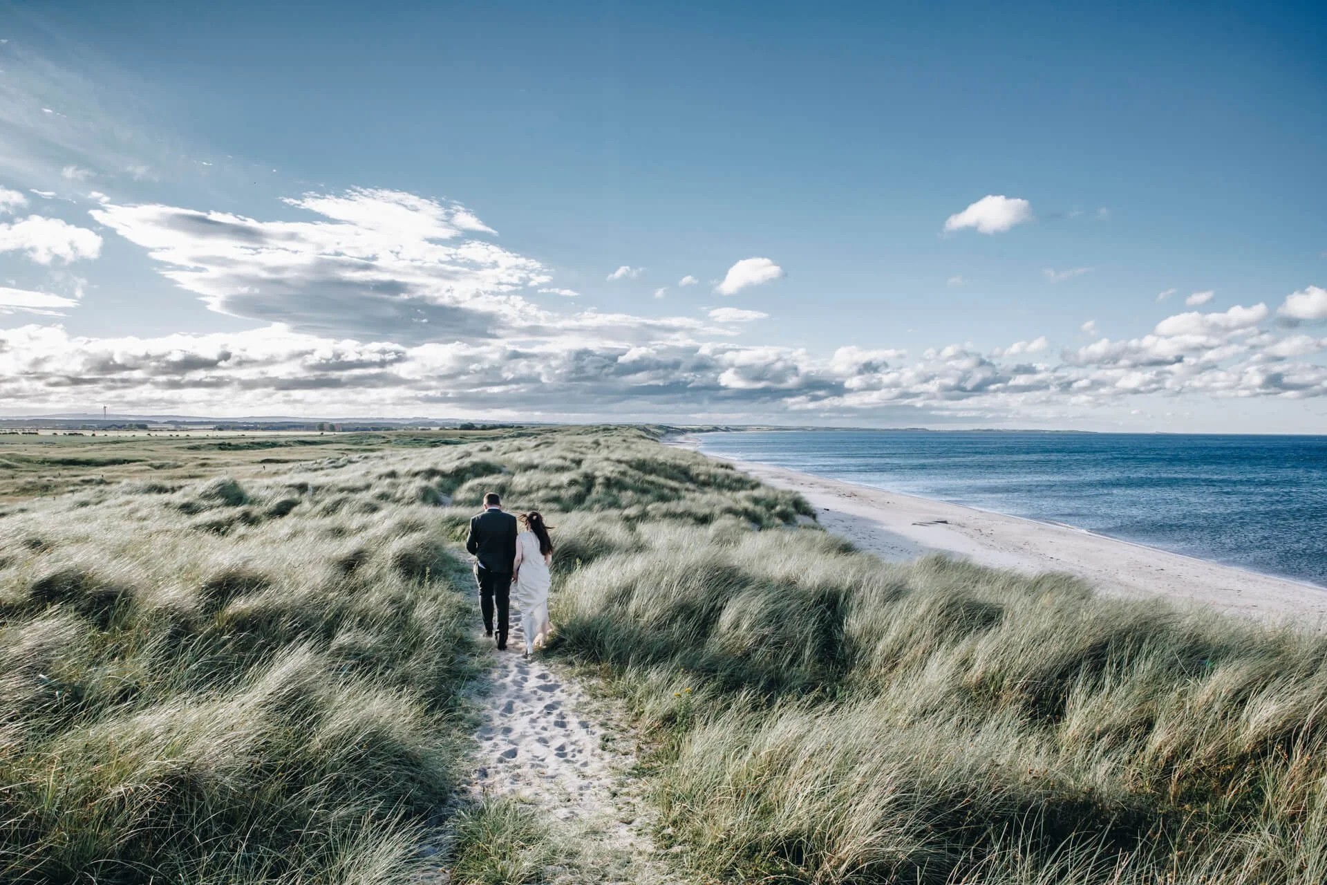 A couple walking along the coast, wedding photography in the North East