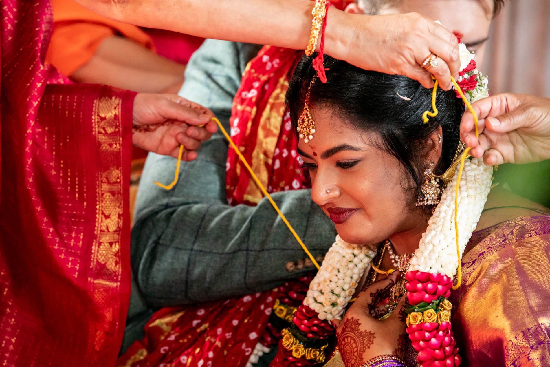 Indian woman in traditional attire being blessed in a wedding ceremony at Bamburgh Castlein the Grand Hall, under a mantap