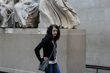  Pictured: A photograph of Phoebe from 2007 (during her high school emo phase), striking a slouchy pose in front of some marble statues. Her dark hair cascades around her face and she wears a dark hooded sweatshirt and jeans. 