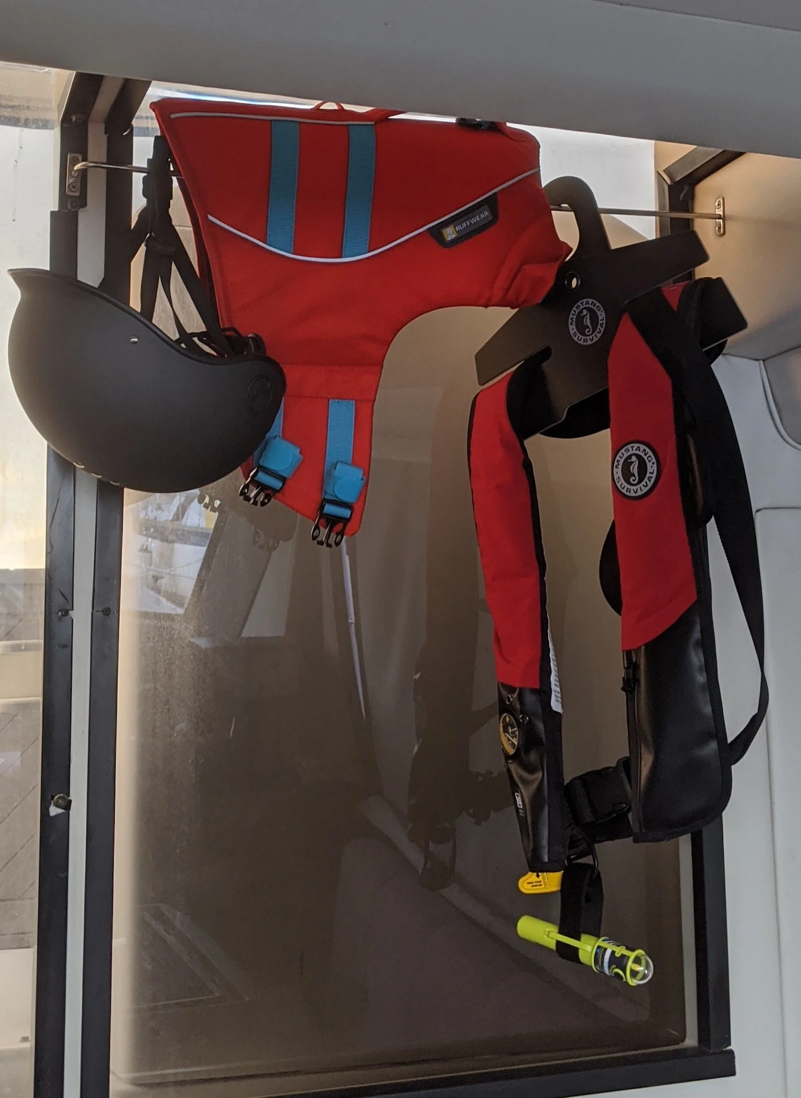 Marine safety gear including Mustang Survival inflatable PFD, Ruffwear dog life jacket, and dive light aboard BlueQuest714