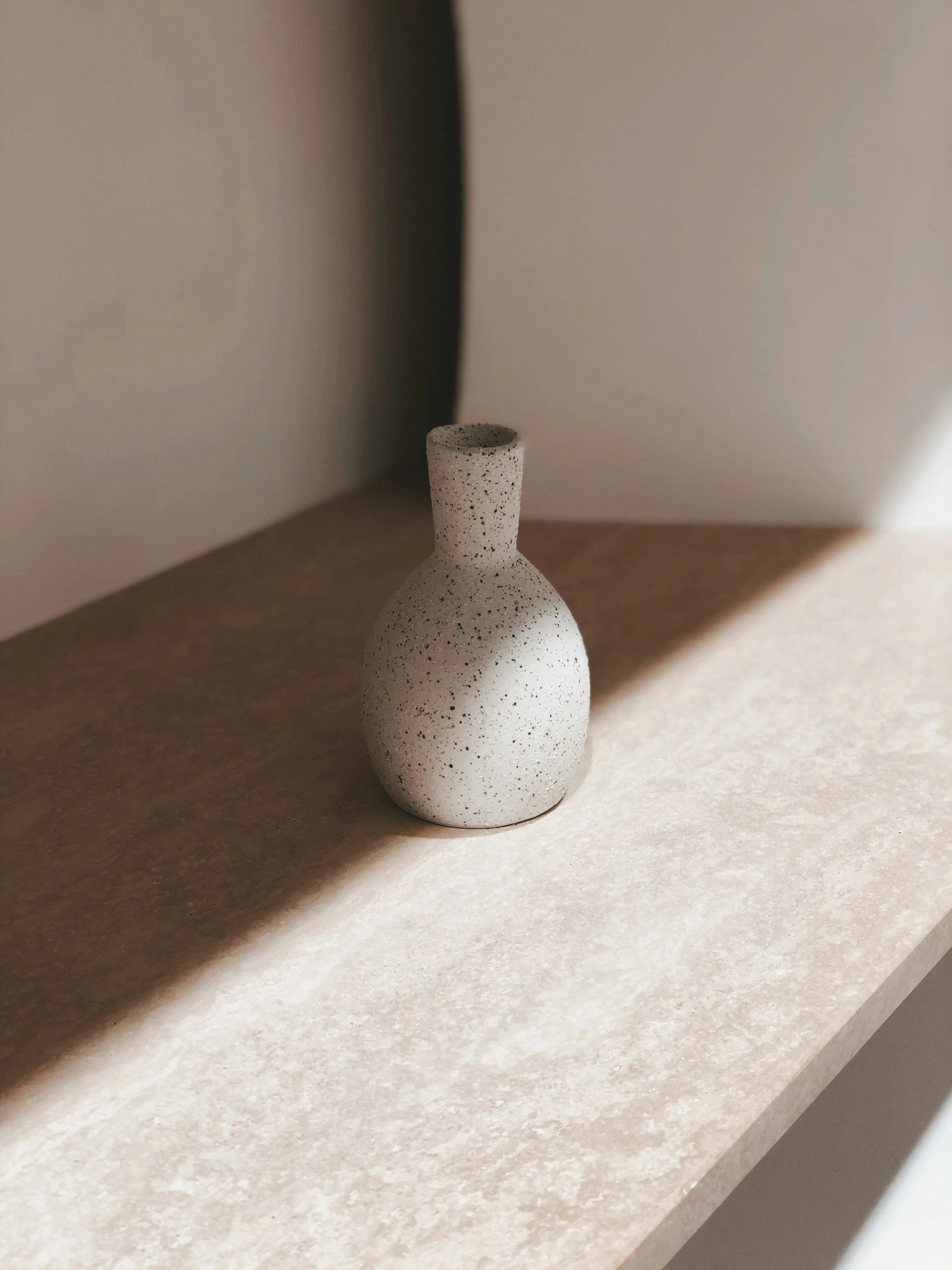 Minimal ceramic vessel placed on a stone surface in soft natural light