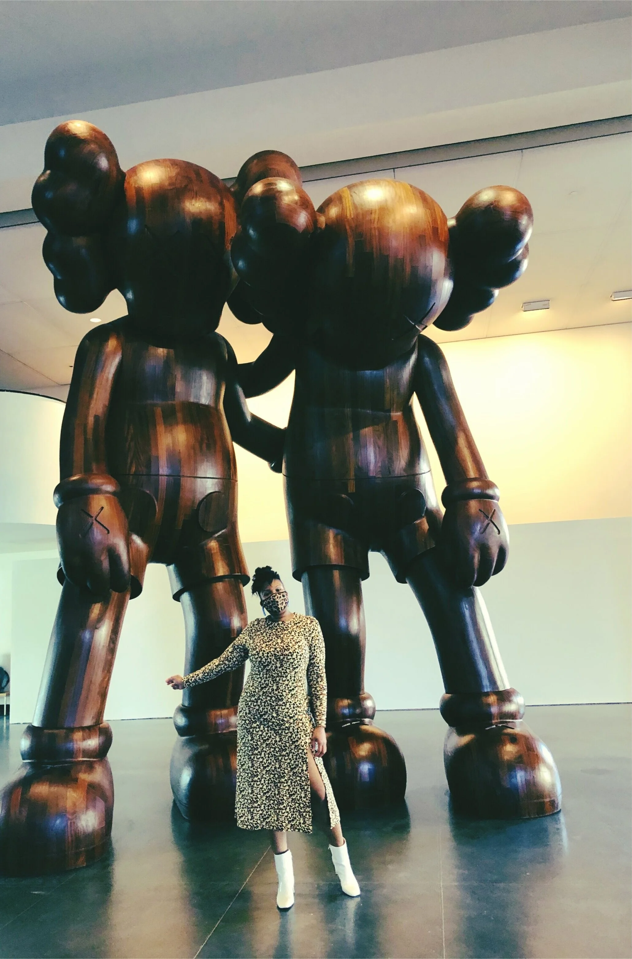 museum exhibit wooden statues; leopard print dress, white booties