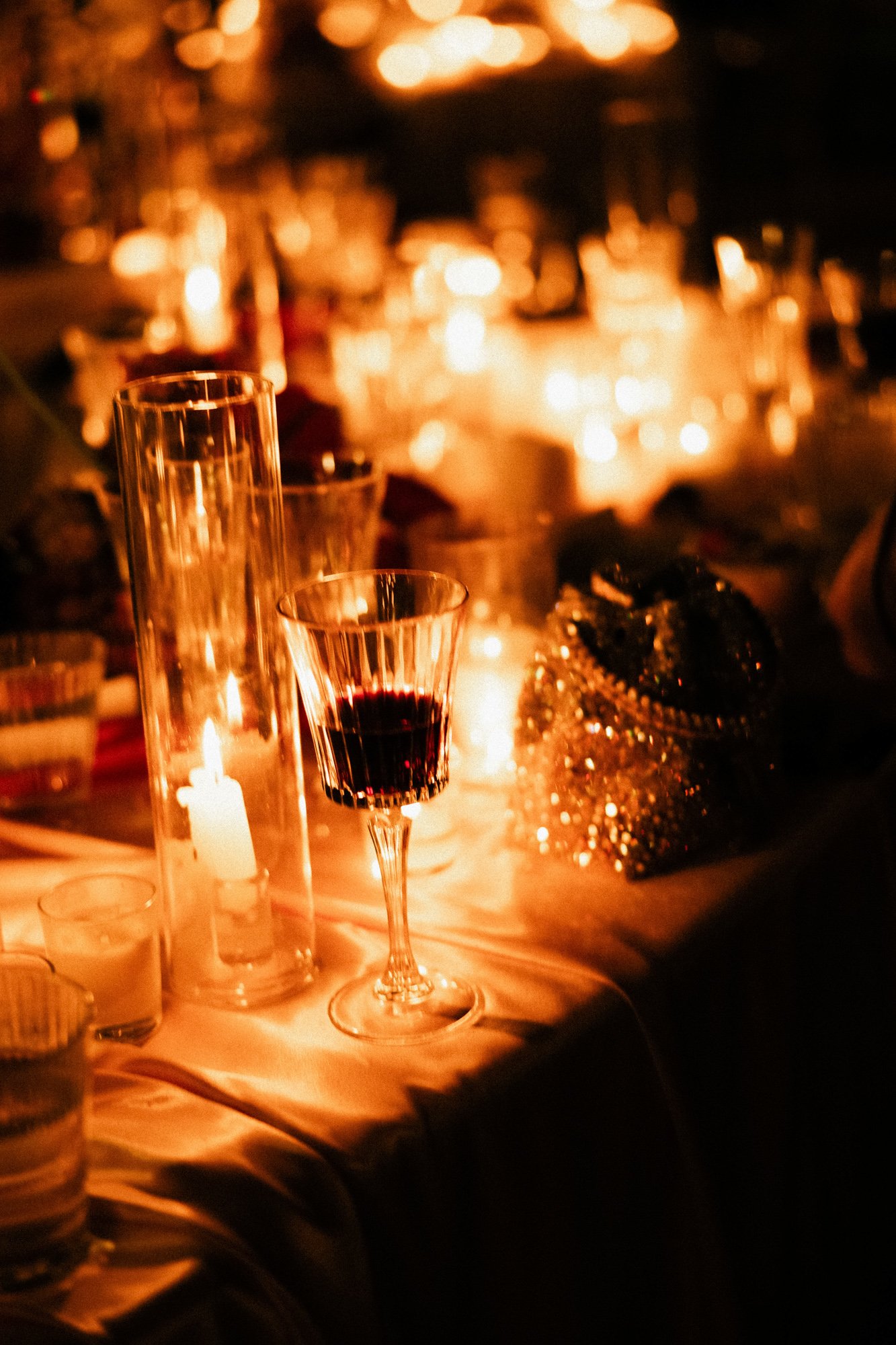 A table set for a celebration with candles, glasses, and decorations in warm lighting.