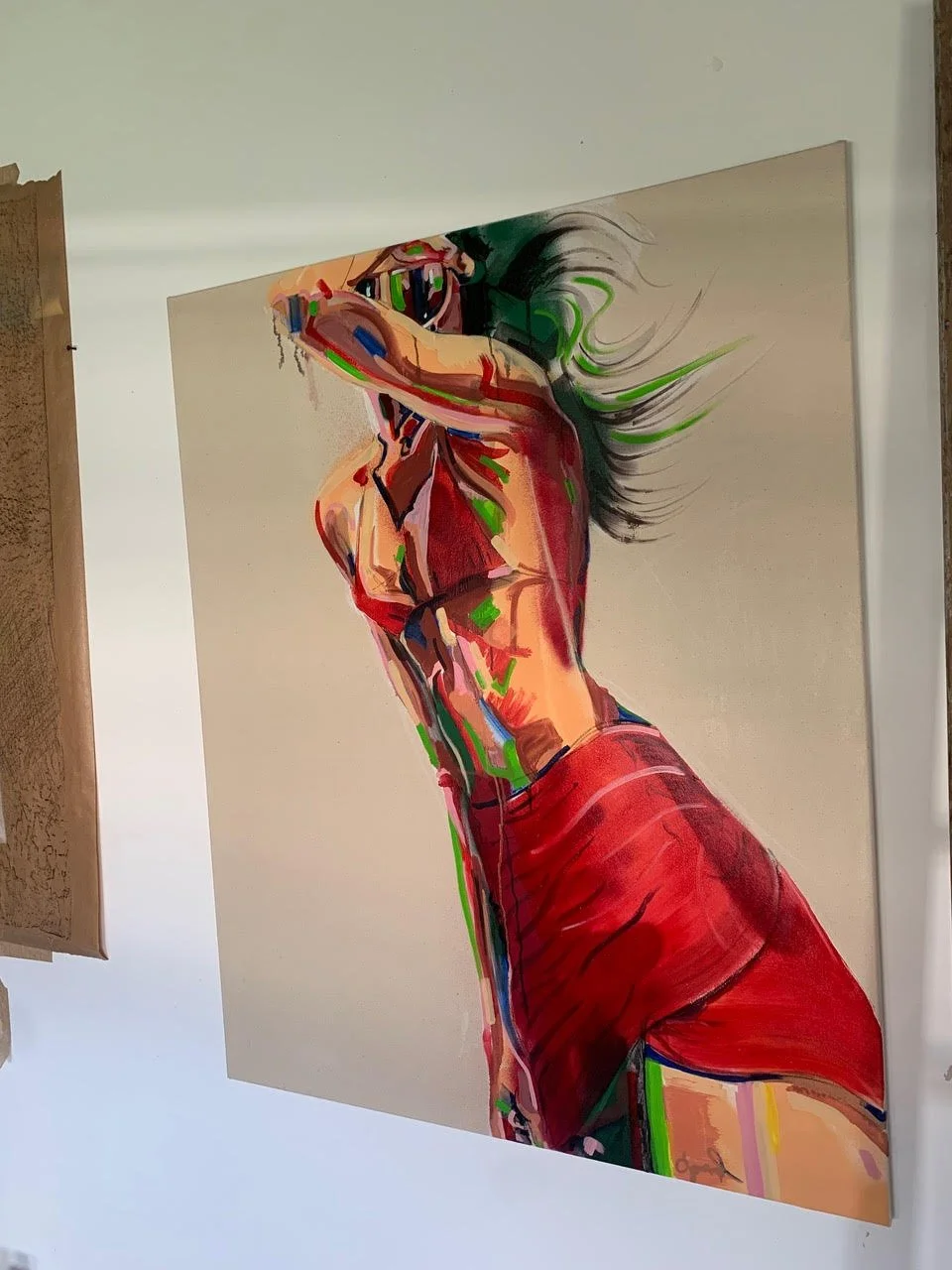 Colorful abstract painting of a woman with long hair, wearing a red skirt, covering her face with her arm.