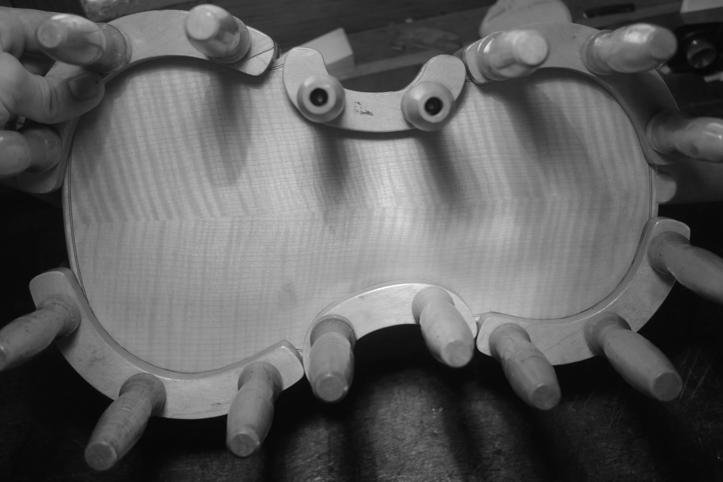 A metal rocket ship mold with wooden pegs around the edges, seen from above in black and white.