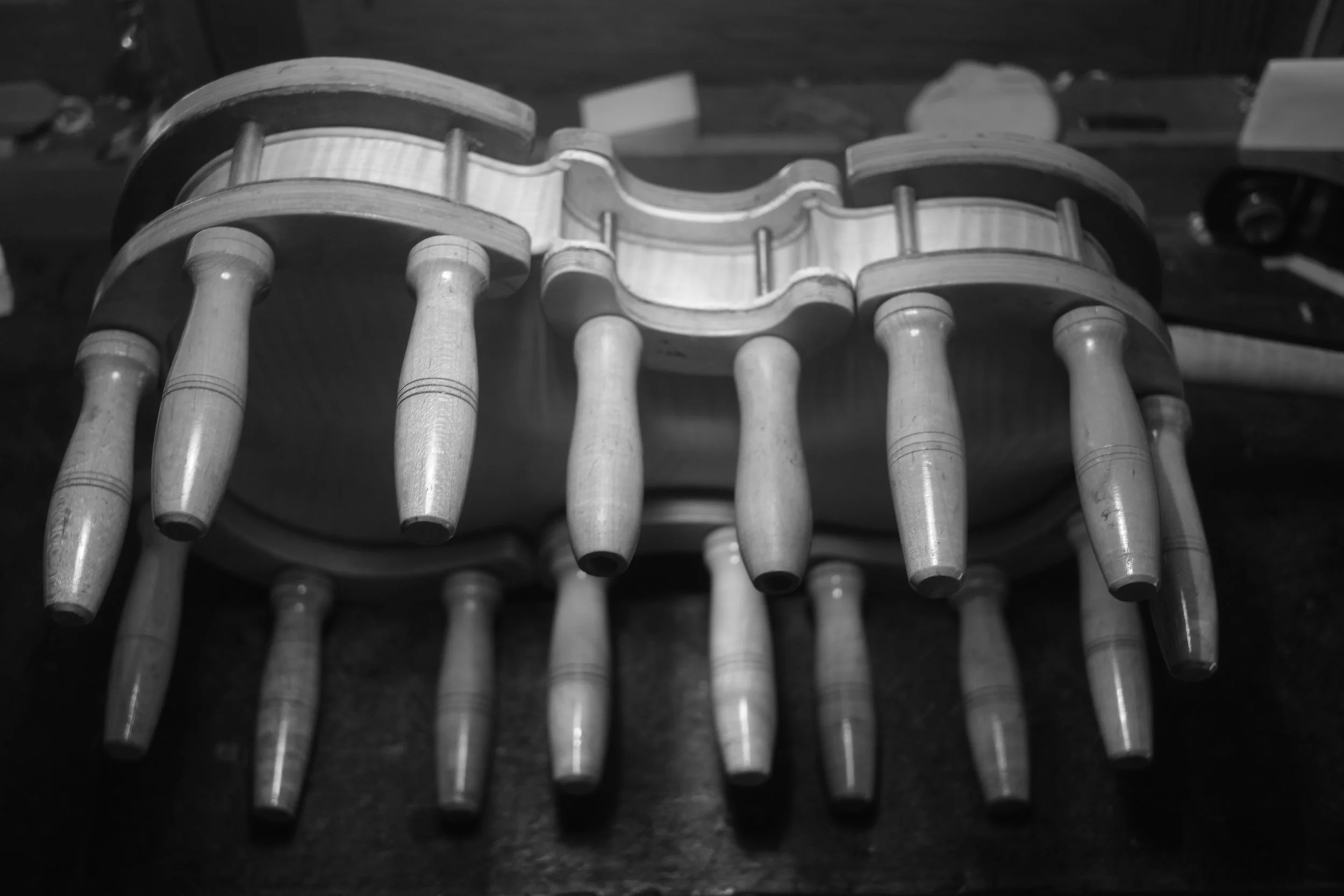 Black and white photo of a wooden craft project with multiple wooden dowels glued to a curved wooden base.