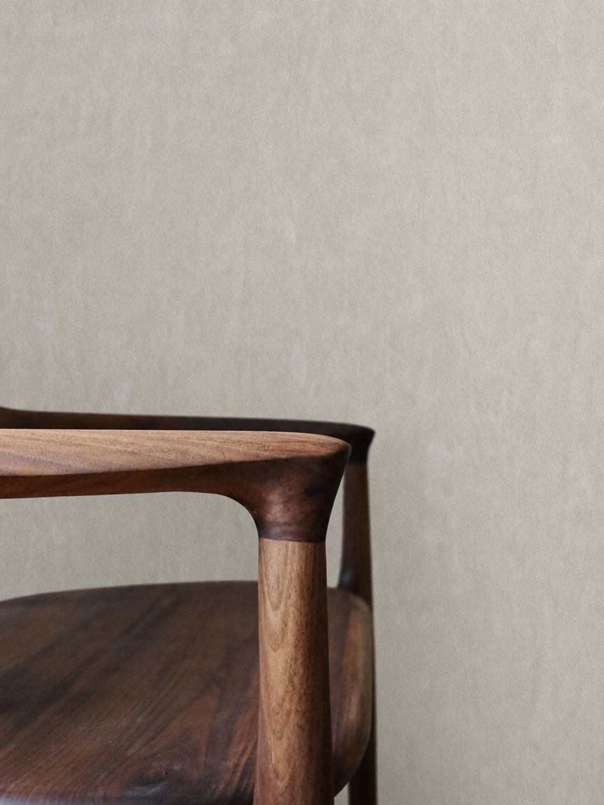 Close-up of a wooden chair with a light-colored wall in the background.