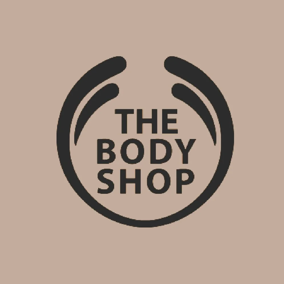 The logo of The Body Shop, featuring black and white design with the brand name enclosed within a stylized circular shape.
