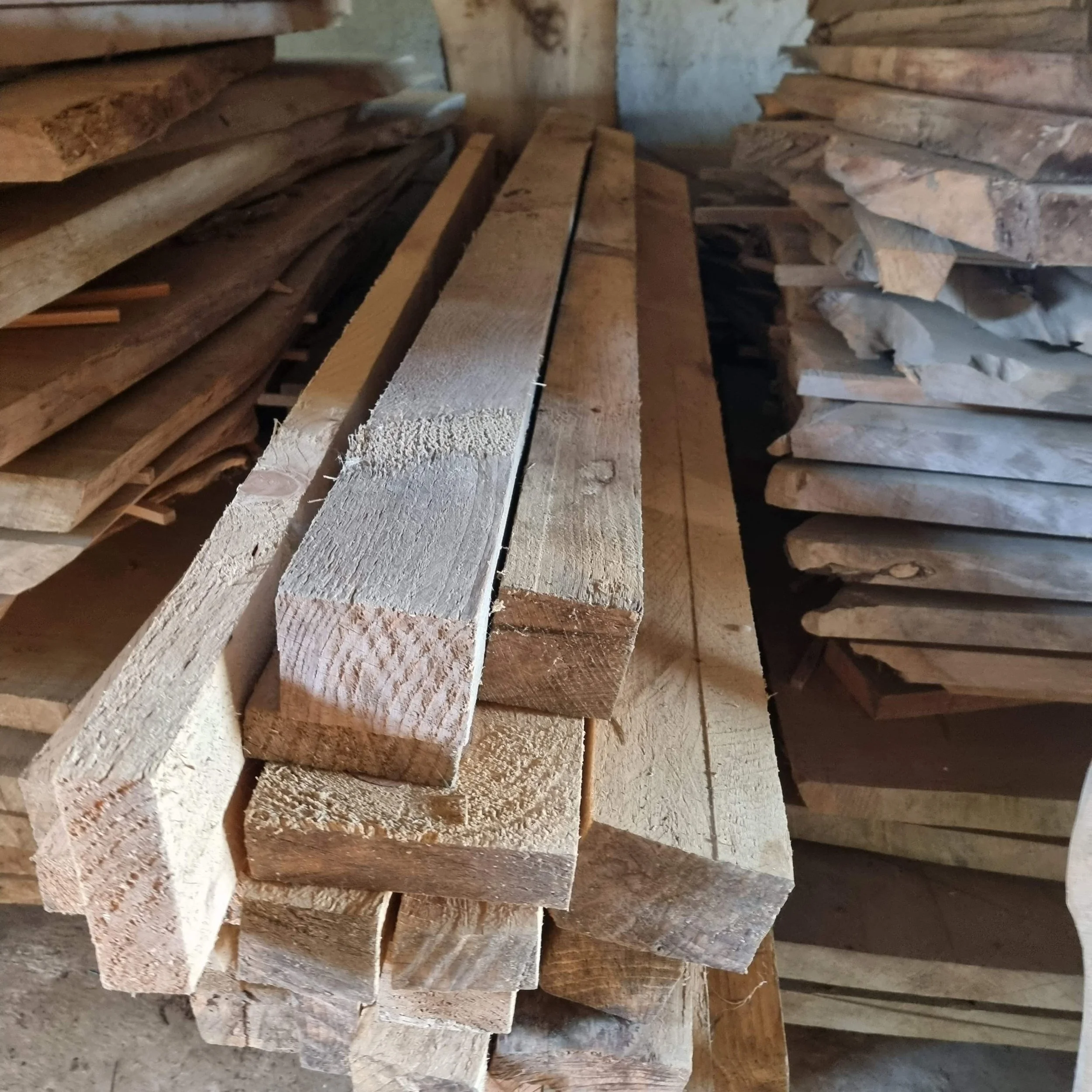 Stacks of rough-cut lumber in a woodworking or lumber storage area.