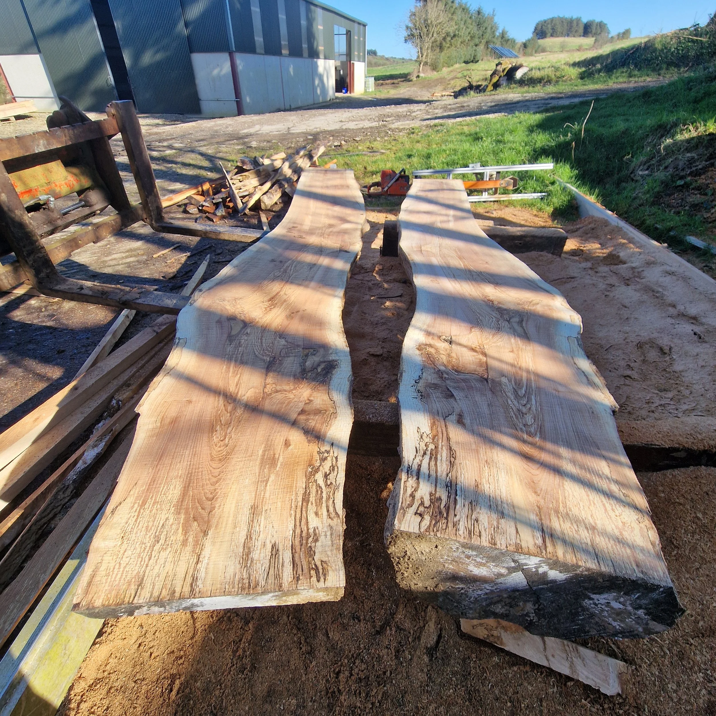 Two large, unevenly shaped wooden slabs on a workbench outdoors at a construction site.
