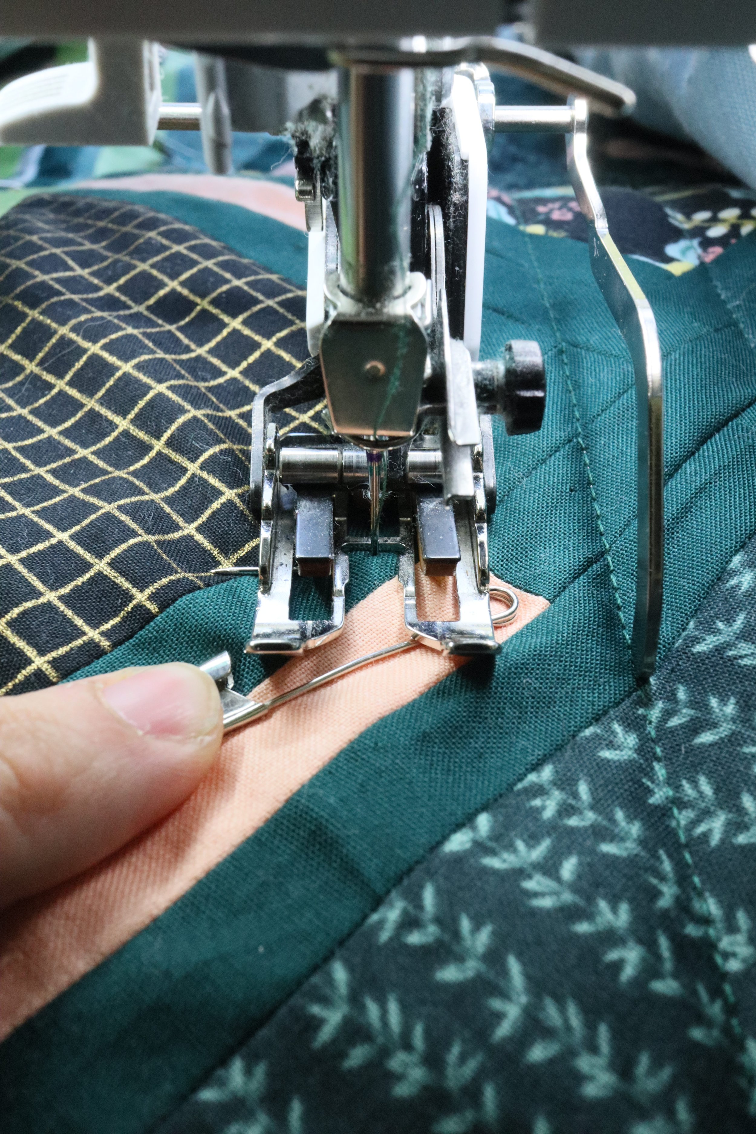 Hold the pin and pull it out just before the needle crosses it.