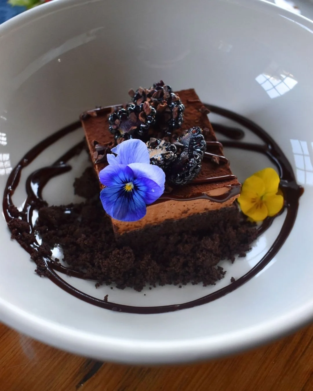 Pure indulgence in every bite with our new chocolate cake layered with silky caramel mousse, cacao nib crunch, and bright bursts of blackberry.🍇