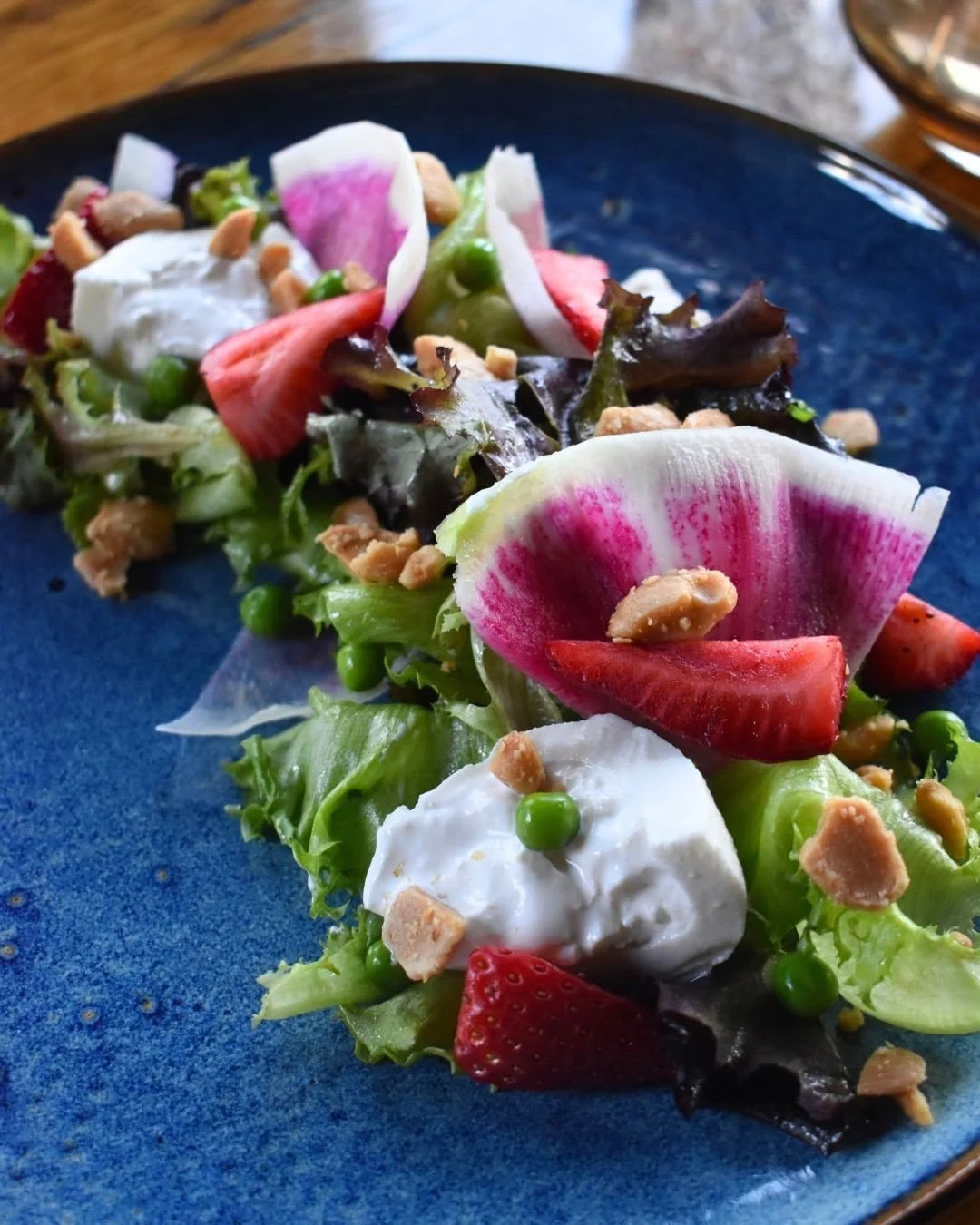 Spring season serves the freshest flavors.🍓 Spring Salad featuring creamy burrata, sweet strawberries, crisp peas, watermelon radish, toasted almonds, and a bright lemon poppy vinaigrette.