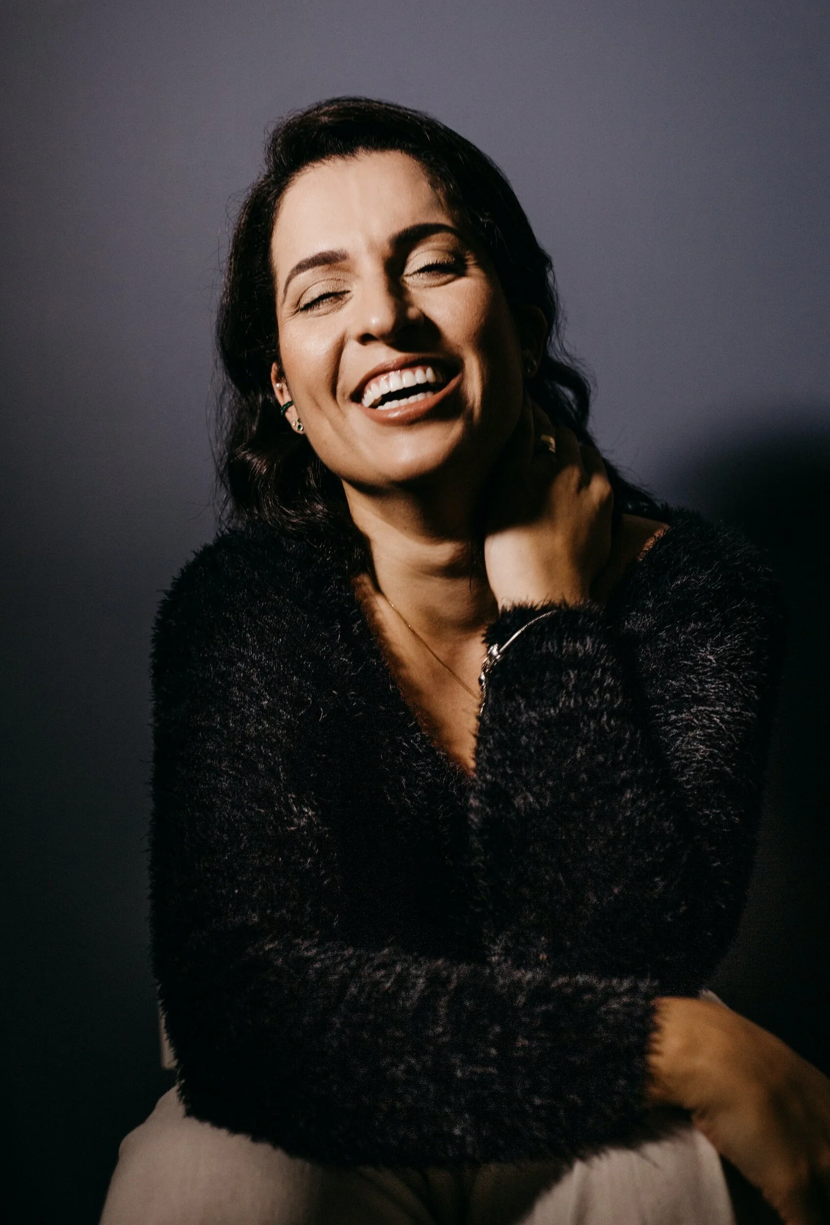 Stock image of a joyful woman with dark hair, paired with a testimonial about craniosacral therapy for nervous system regulation, pain relief, and emotional healing with Dr. Megan Marie.