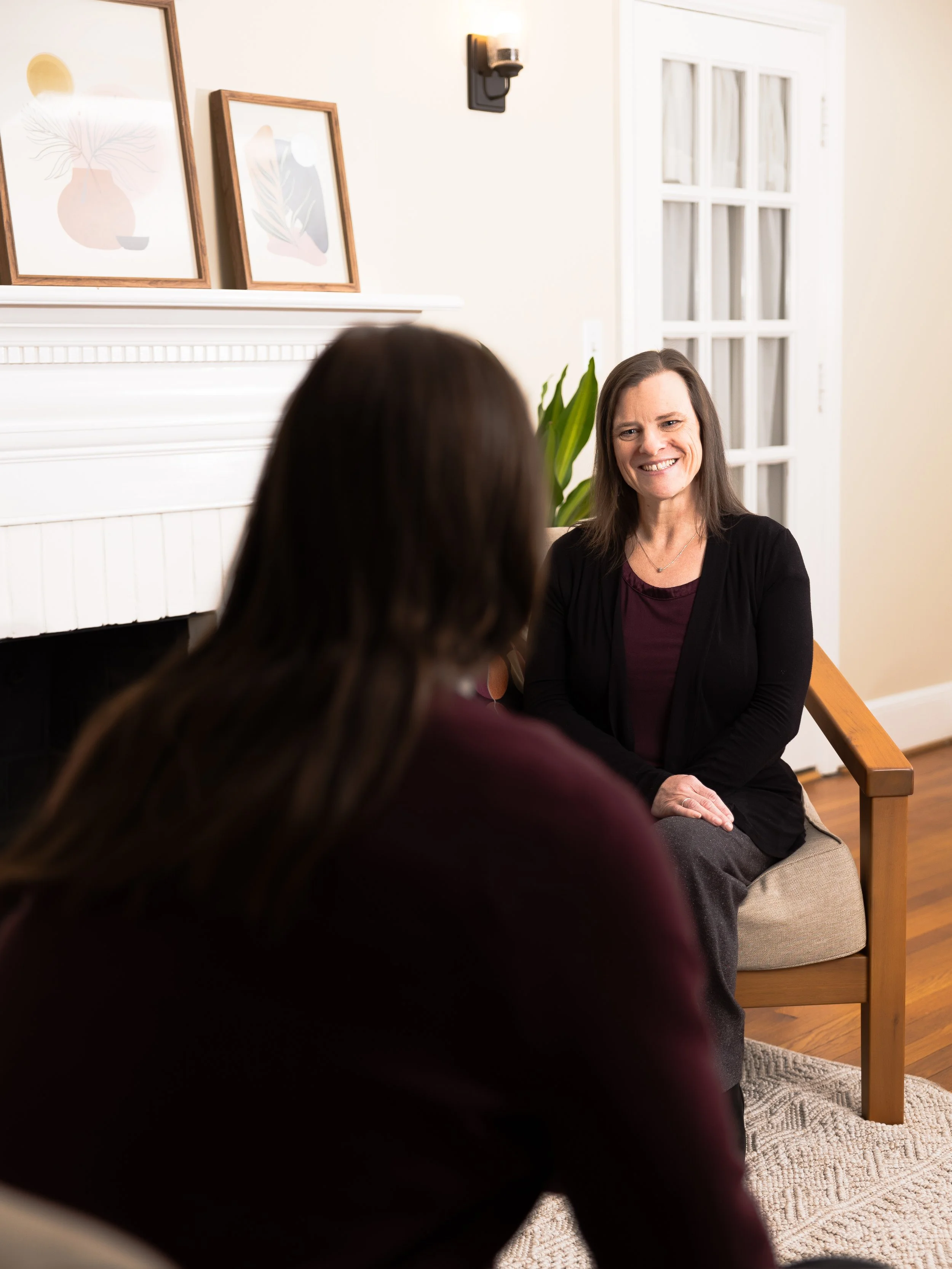 Jen smiling in a chair, having a session