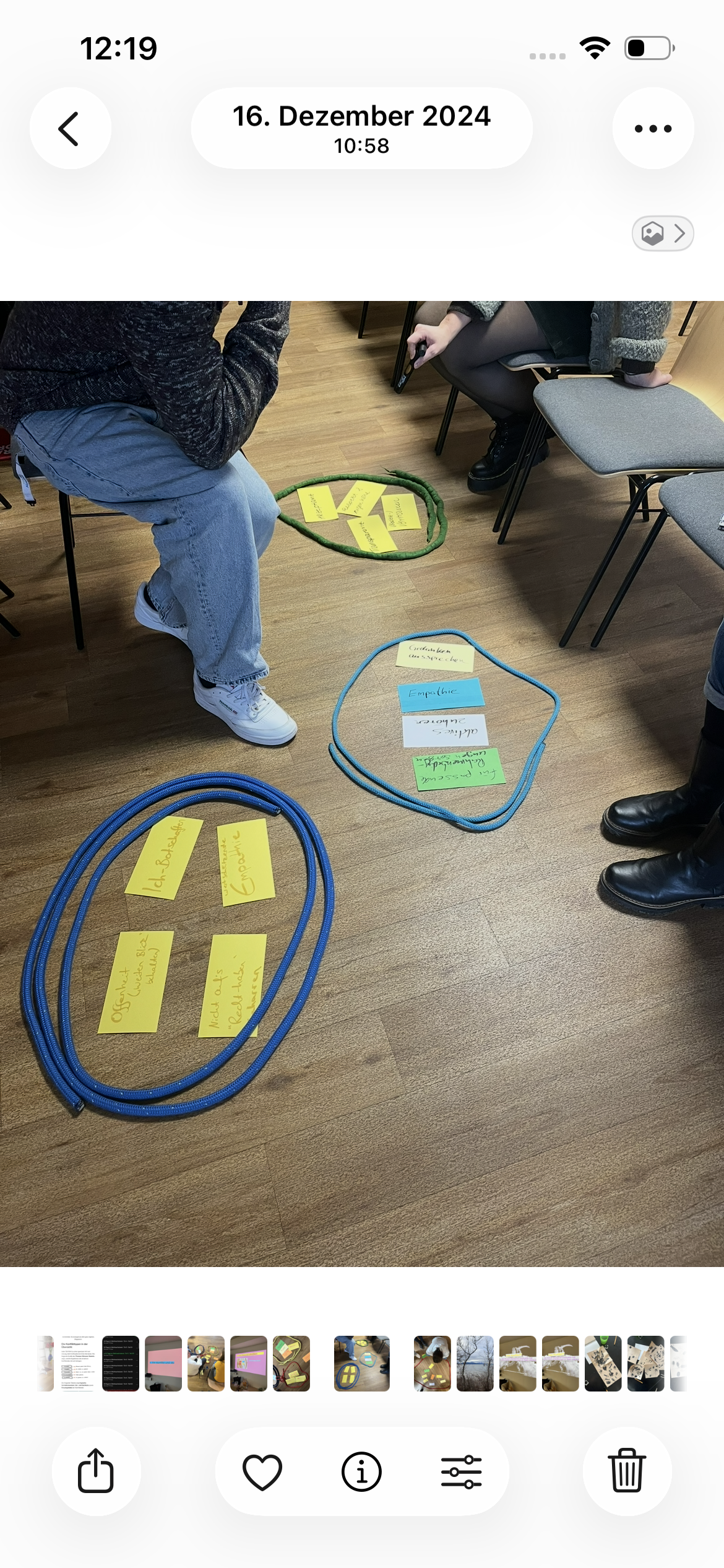 Zwei Personen sitzen in einem Raum, auf dem Boden haben sie Post-its mit Text.