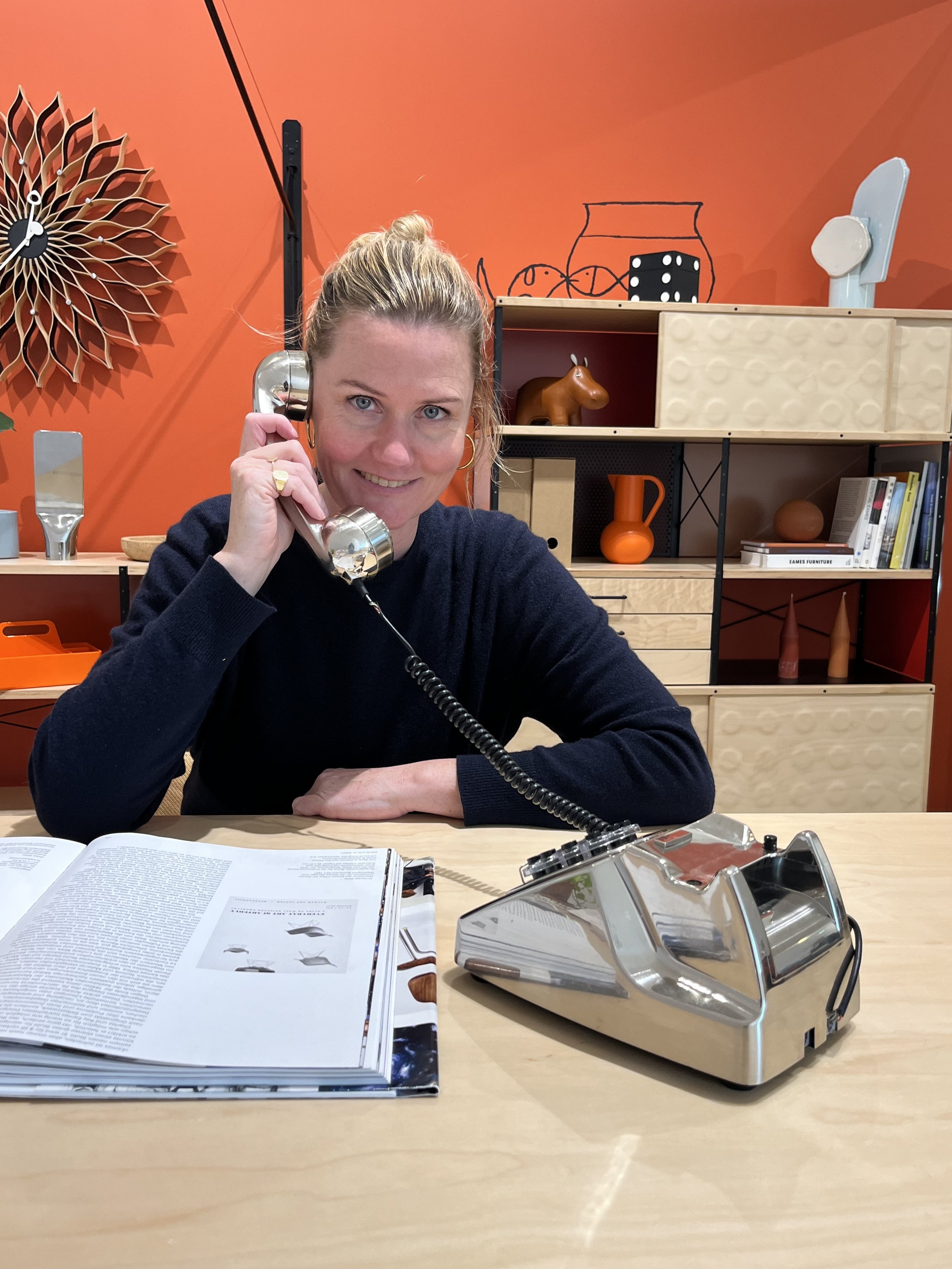 Katharina an einem Schreibtisch mit Telefonhörer am Ohr