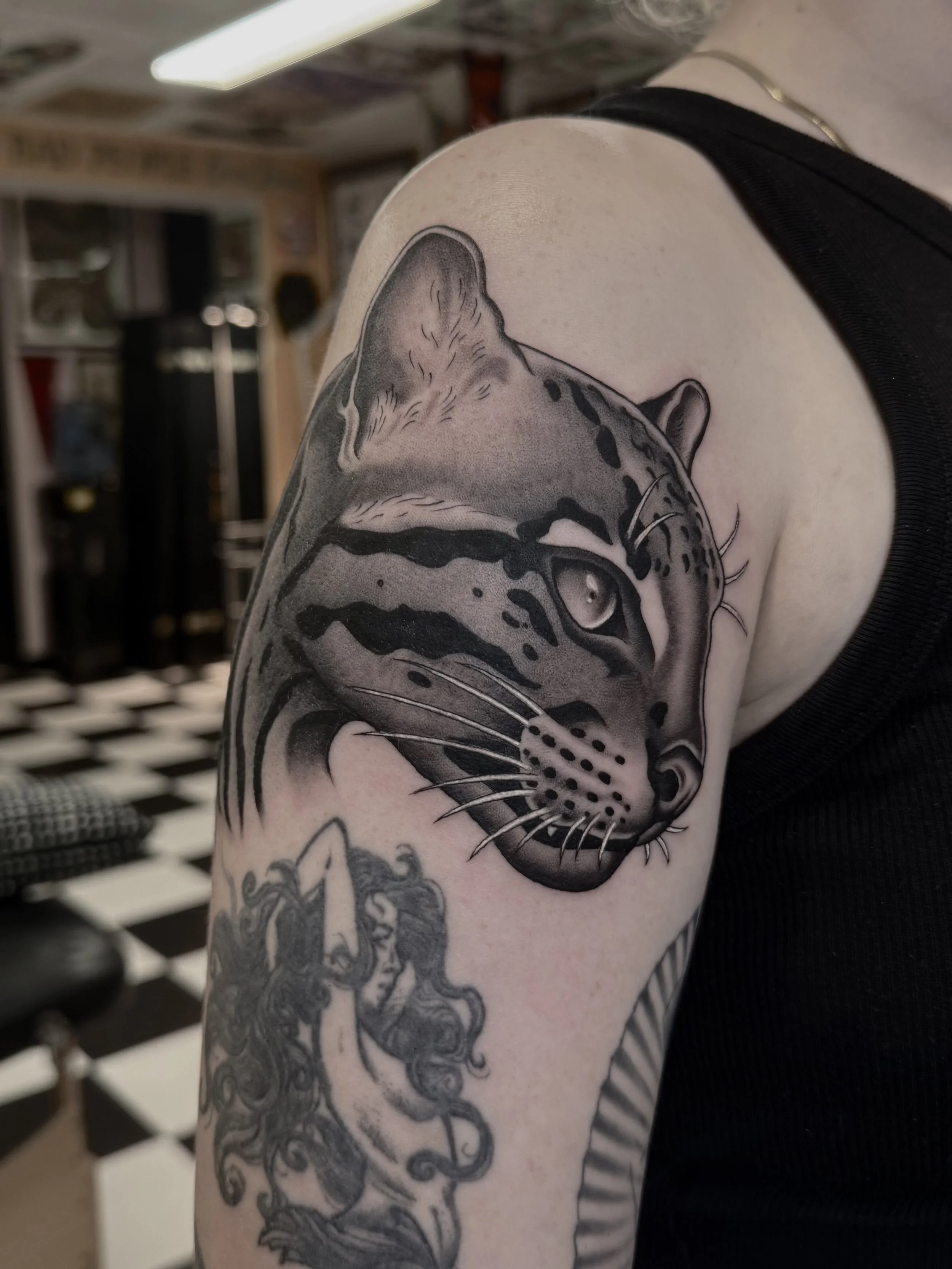 Black and grey tattoo of a tiger's face on a person's upper arm.