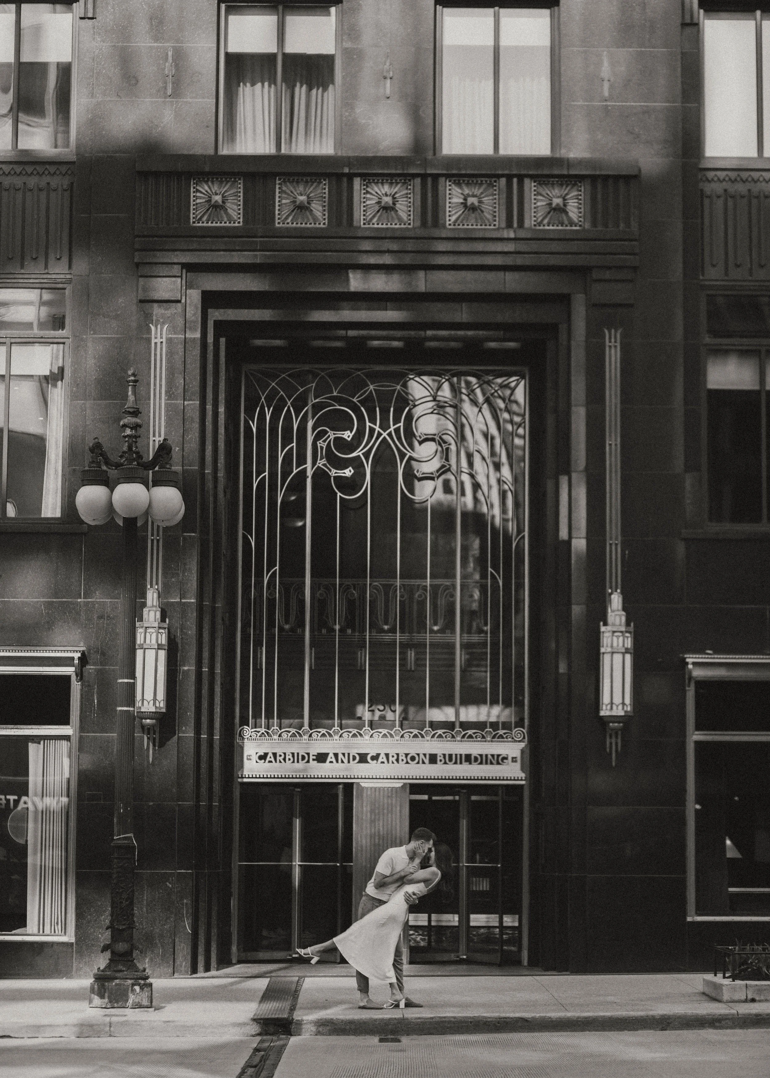 A couple kissing in front of the Carbide and Carbon Building in Chicago, black and white photo.