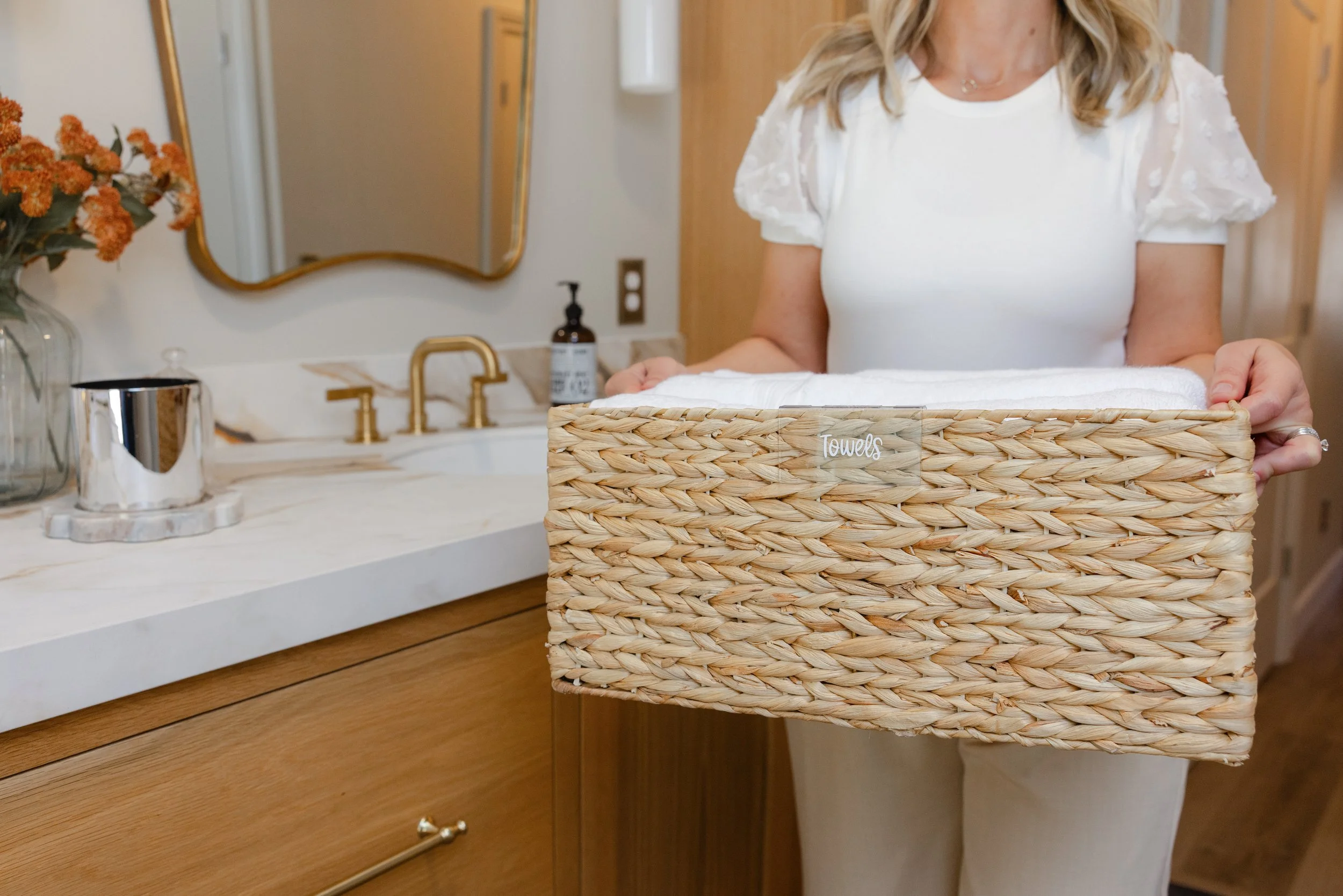 Labeled linen basket with neatly folded towels in an organized bathroom by professional organizer in Stockton and Lodi, The Simple House