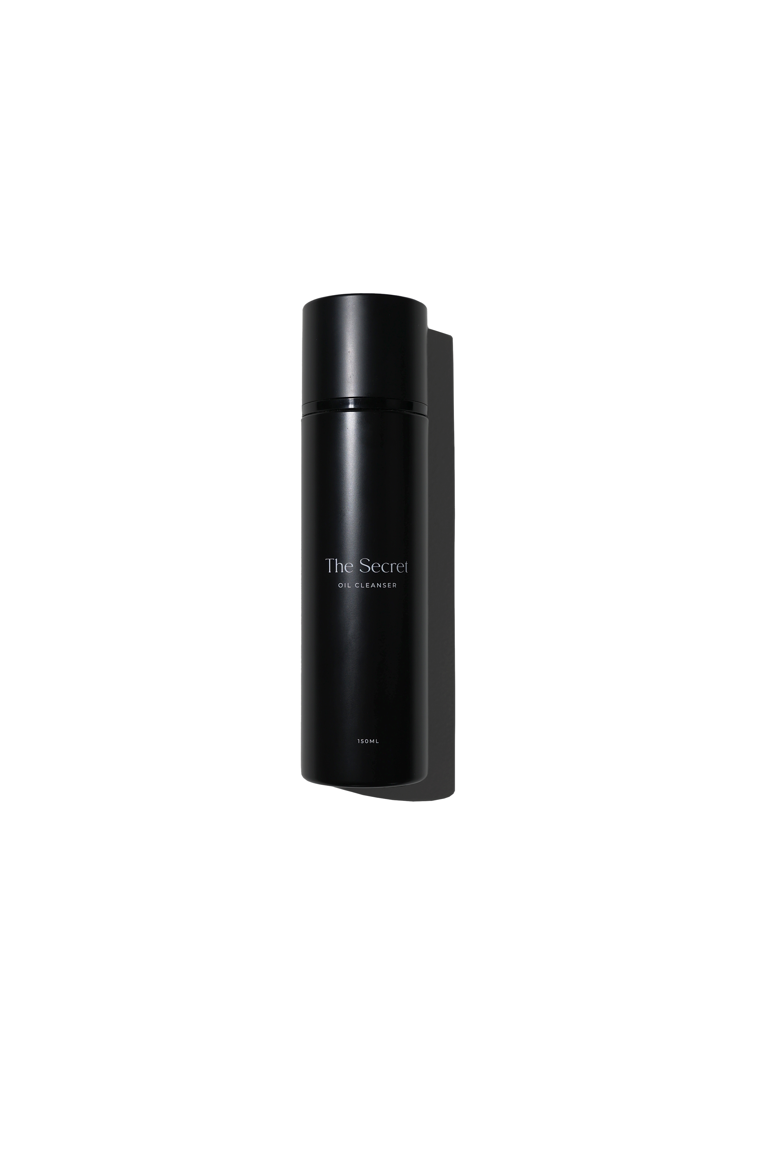 A black cylindrical bottle labeled 'The Secret Oil Cleanser' against a background divided into black and white sections.