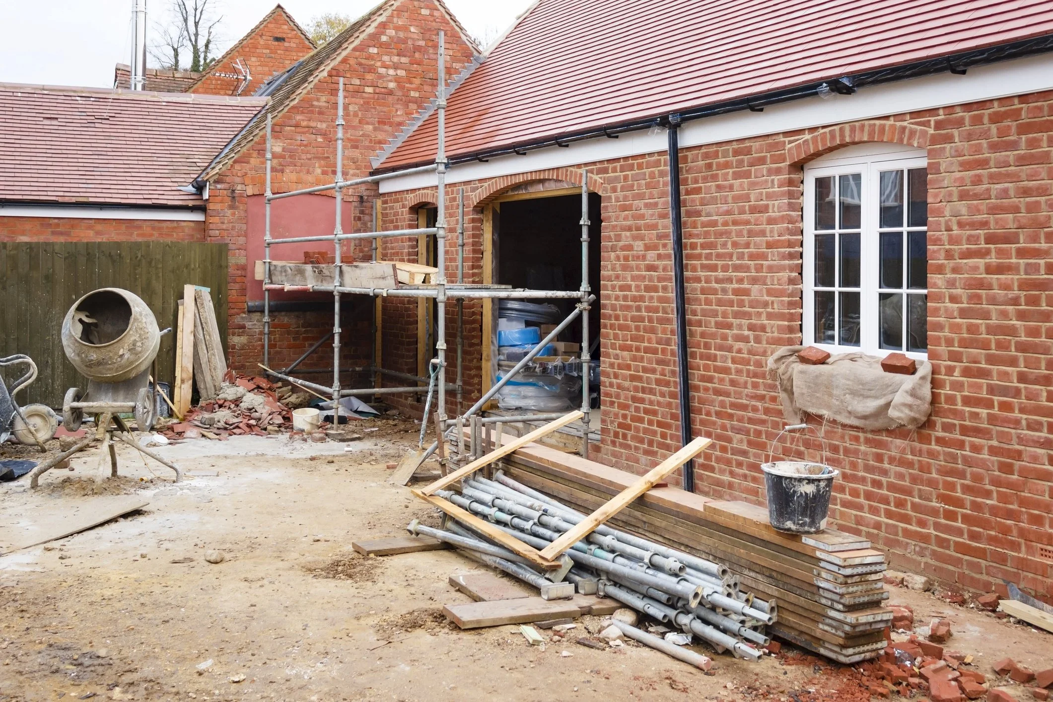 Construction site with unfinished brick building, scaffolding, and masonry tools.