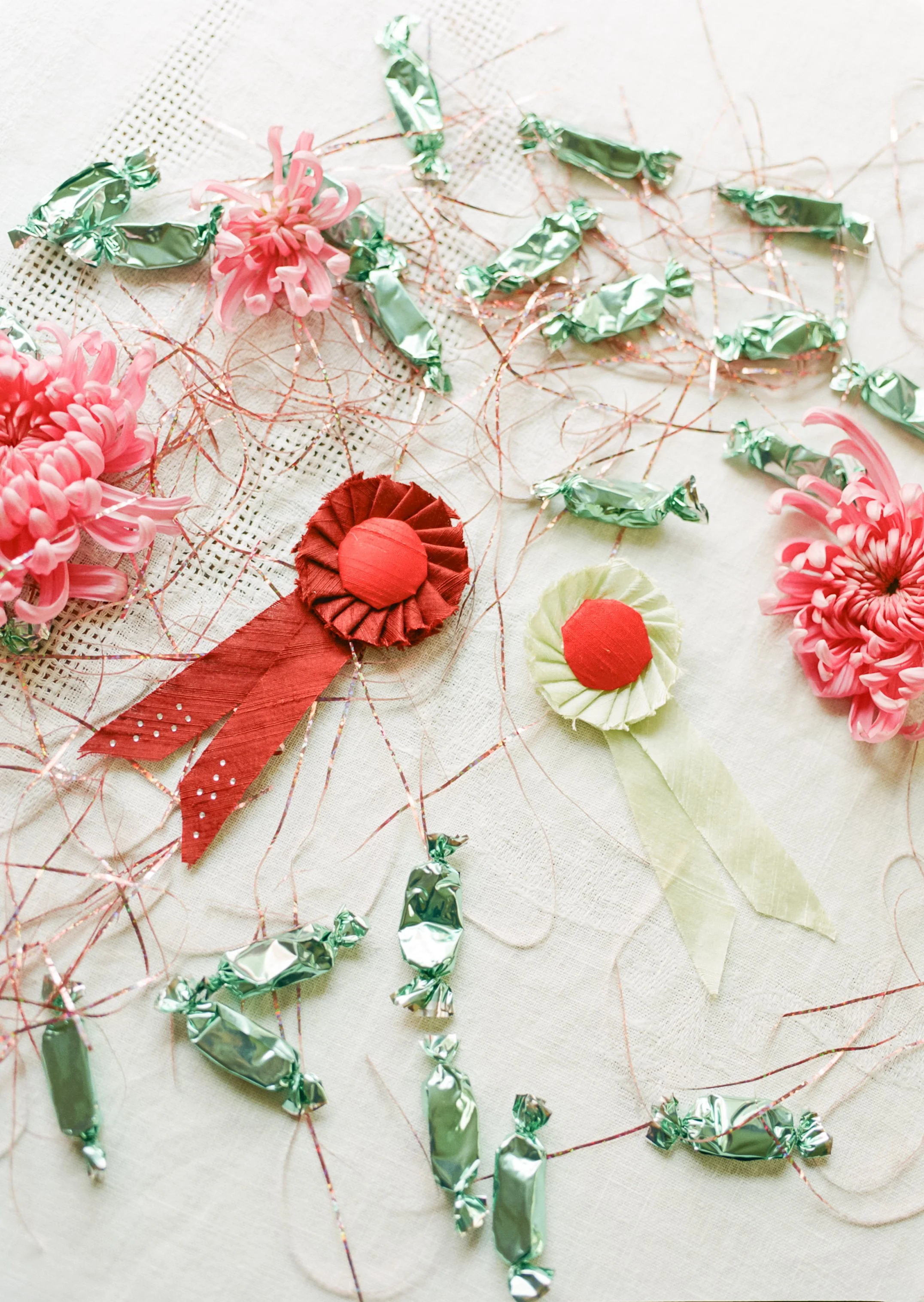 Silk award ribbons with blue foil candies and pink tinsel on a white linen tablecloth