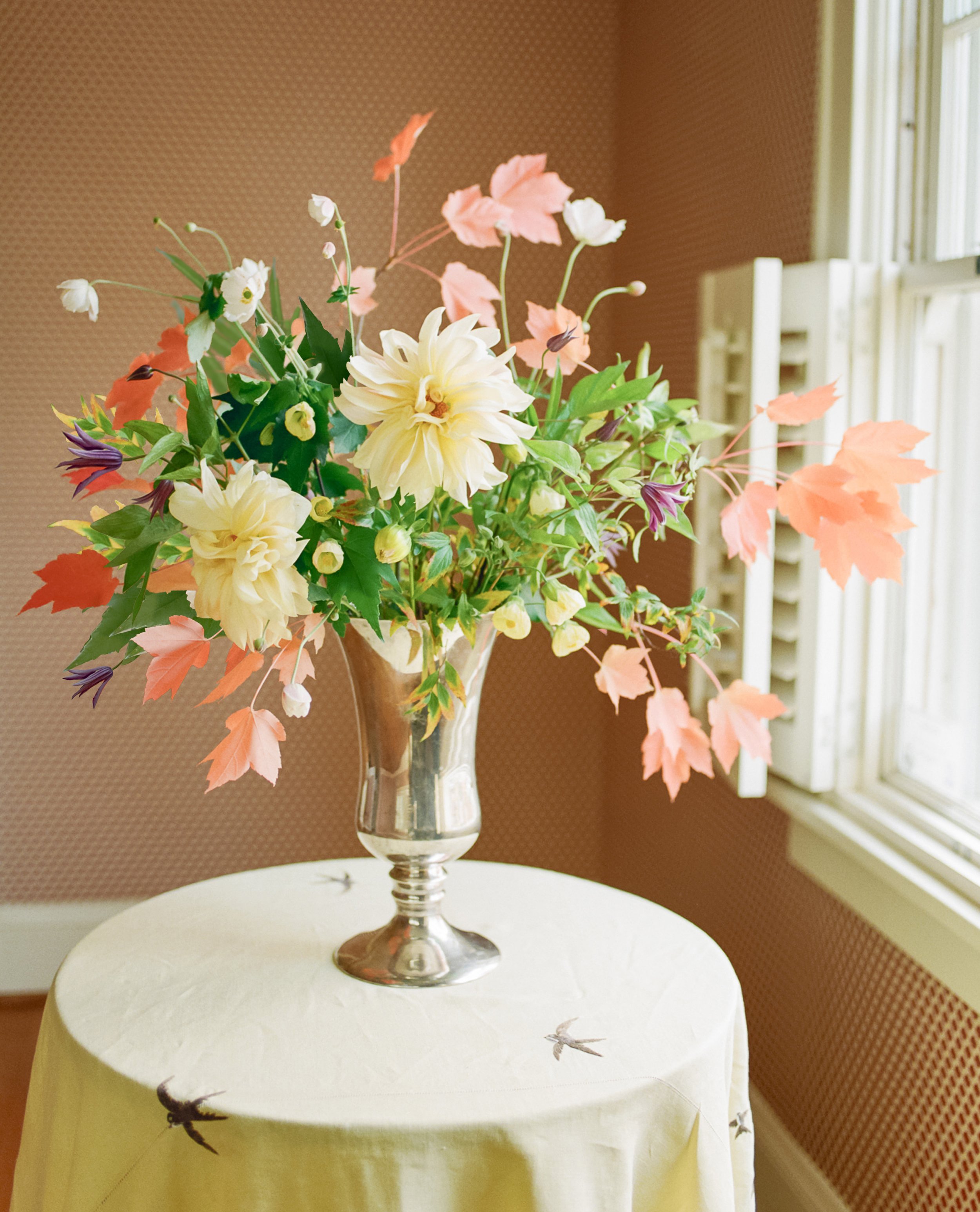 Floral arrangement by Hattie McLean with dahlias, flowering maple, clematis, anemones, and red maple leaves